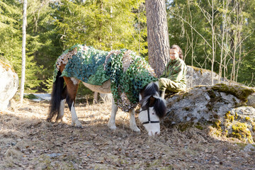 Fototapeta premium Camouflaged icelandic horse and woman in Finnish spring enviroment