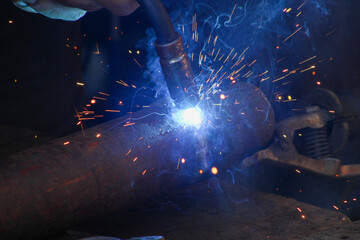 Working with a welder on a wooden table, close up
