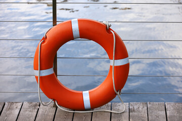 Orange lifebuoy on a beach. Safety on a water, life ring on wooden pier