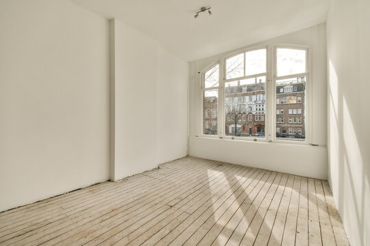 an empty room with white walls and wood flooring, looking out onto the street from one corner to the other Generative AI