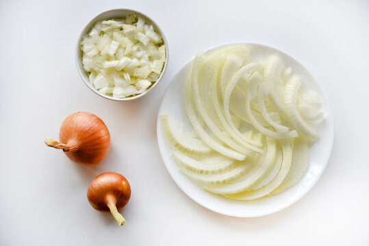 Two onions and chopped onion on a white plate. Onion on a white background.