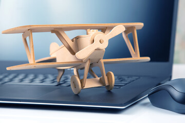 Model of a wooden plane on the background of a laptop. Business development and success. Dream to fly in your favorite business.