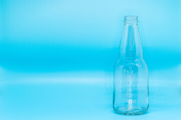 Glass bottle isolated on blue background, beer, soda, sparkling water, juice, label desing, selective focus, front view