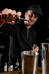 Bartender prepares classical Clover club alcoholic cocktail at the bar. Bartender mixes egg white, lemon, dry vermouth and gin to prepare the Clover club cocktail.