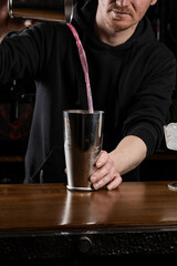 Bartender mixes egg white, lemon, dry vermouth and gin to prepare the Clover club cocktail. Barman prepares classical Clover club alcoholic cocktail at the bar.