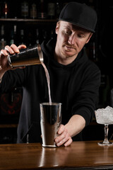 Bartender prepares classical Clover club alcoholic cocktail at the bar. Bartender mixes egg white, lemon, dry vermouth and gin to prepare the Clover club cocktail.