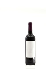Full unopened bottle of red wine with blank label isolated on a plain white background. Copy space left and above.