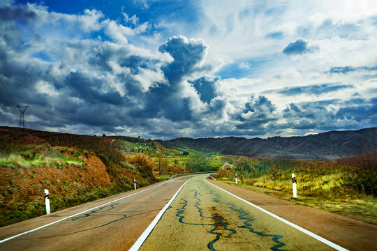 Concepto de viaje en coche y carretera.Carretera de monta&ntilde;a vacia hacia el horizonte en un dia nublado de tormenta.