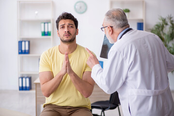 Obraz premium Young male patient visiting old male doctor