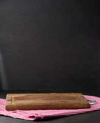Empty wooden cutting board and red towel on black background.
