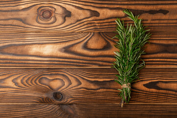 Dried rosemary in a bowl and branches of fresh rosemary on a vintage brown wooden background. Spicy spices for cooking meat and fish. Recipe. Fresh rosemary herb. Place for text, space for copy.
