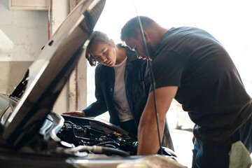 Trying to identify the source of the problem. two mechanics working together on a car in an auto...