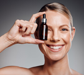 Fototapeta premium Beautiful mature woman posing with beauty treatment in studio against a grey background
