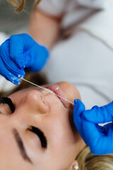 Professional permanent make up procedure. Tattoo lips makeup treatment in modern beauty salon.