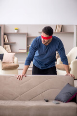 Blindfolded young man at home