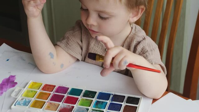 Toddler home leisure activity. Little boy using watercolors to create painting.  Generative AI