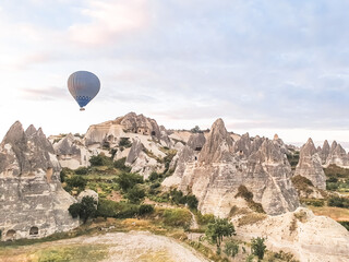 Flying in sky many bright colored beautiful balloons into air in Cappadocia in mountains early at sunrise, dawn. Filling balloon with hot air from burner, big basket. Tourists excursion, cloud flight