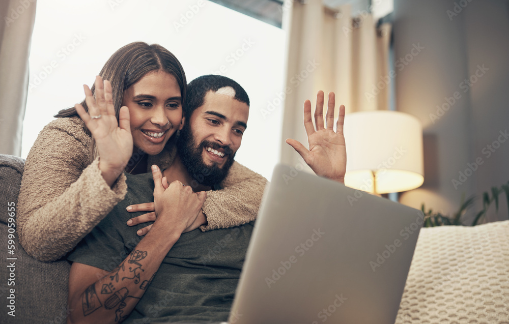Poster hello from half way across the world. a young couple using a laptop to make a video call on the sofa