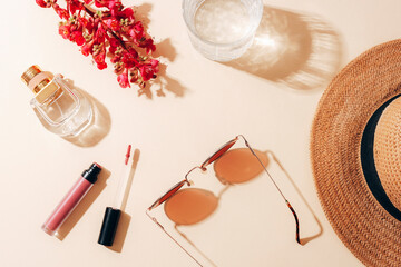 Flat lay with women's summer accessories on neutral background. Sunglasses, straw hat, lipstick,...