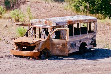 Old burned out rusted school bus sitting in vacant field