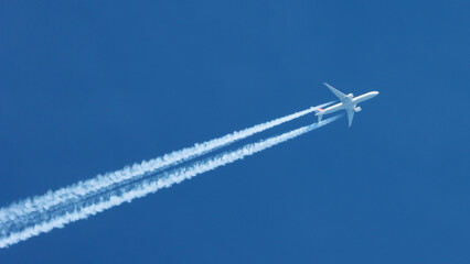 Jet airplane flying overhead in clear blue sky diagonally with condensation trail - obrazy, fototapety, plakaty