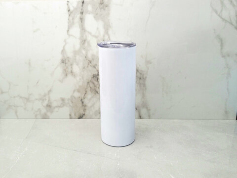 20oz blank tumbler against marble backdrop and marble surface.