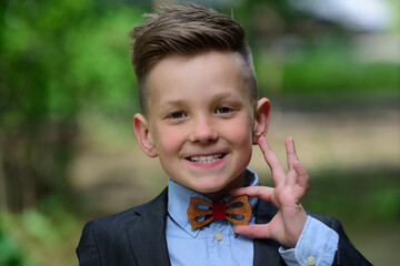 Little fashion portrait of kid boy in suit and bow tie. Outdoor closeup portrait of funny kids face. Summer kid outdoor portrait. Close up face of cute child. Kid having fun outdoor on summer day.