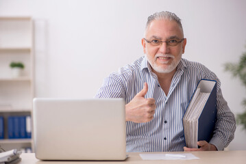 Old male employee working at workplace