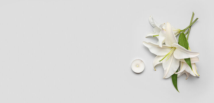 Beautiful lily flowers and candle on white background with space for text