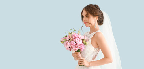Portrait of beautiful young bride with wedding bouquet on light blue background with space for text