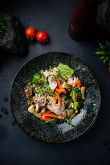 Salad with chicken, cucumbers, lettuce, sweet pepper, avocado, arugula and sesame seeds.