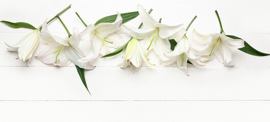 Delicate lily flowers on white wooden background, top view