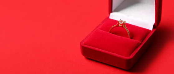 Box with engagement ring on red background with space for text, closeup