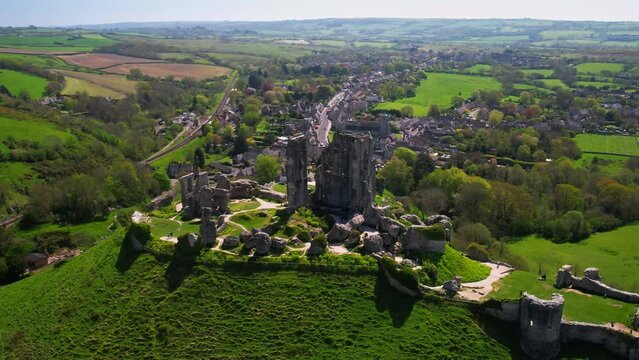 Telephoto aerial shot circling the ruins of Corfe Castle in Dorset with village and countryside in background