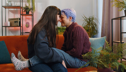 Portrait of two young lesbian women family couple. Girls embrace hug each other at home indoor....