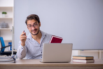 Fototapeta premium Young male teacher sitting in the classroom