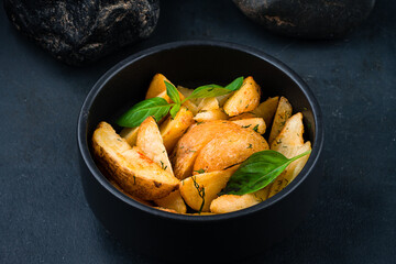 Rustic fried hot potato wedges with salt and greens, fast food in a bowl.