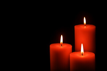 Fototapeta na wymiar Three red candles black background