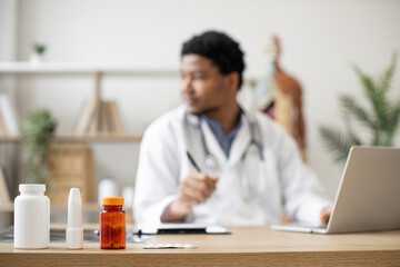 Focus on medication containers on doctor's office desk being prescribed by medical specialist in...
