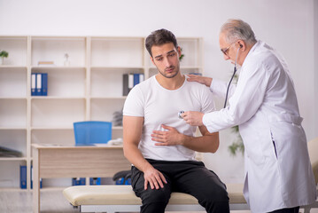 Fototapeta premium Young male patient visiting old male doctor