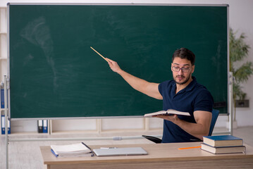 Young male teacher sitting in the classroom
