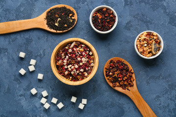 Composition with different types of dried fruit tea and sugar on blue grunge background