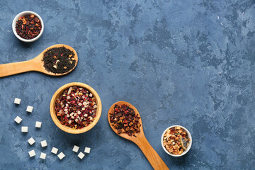 Composition with different types of dried fruit tea and sugar on blue grunge background