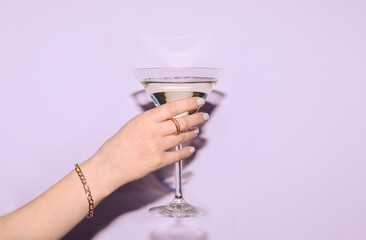 Woman with glass of martini on lilac background