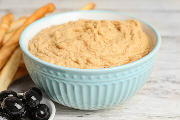 Bowl with tasty hummus on light wooden background, closeup