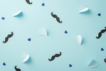 Funny and trendy Father's Day theme. Overhead shot of mustache, and hearts on pastel blue backdrop