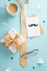 Fototapeta na wymiar Fashionable Father's Day design. Top vertical view of beige necktie, spectacles, accessories, giftbox, craft paper envelope, postcard with mustaches, coffee mug on pastel blue background