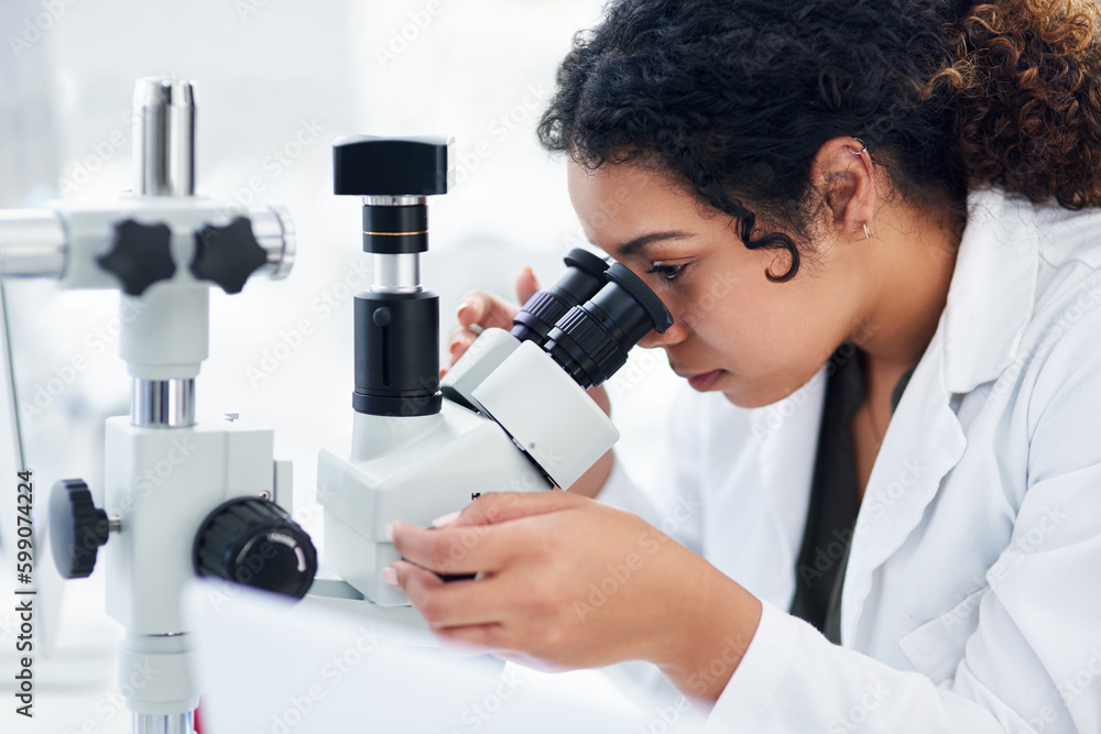 Aufkleber Taking a closer look. a young female scientist using a microscope in a laboratory.