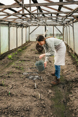 pretty woman watering the seedlings in a big greenhouse