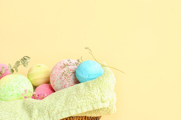 Towel with bath bombs and flowers on beige background, closeup